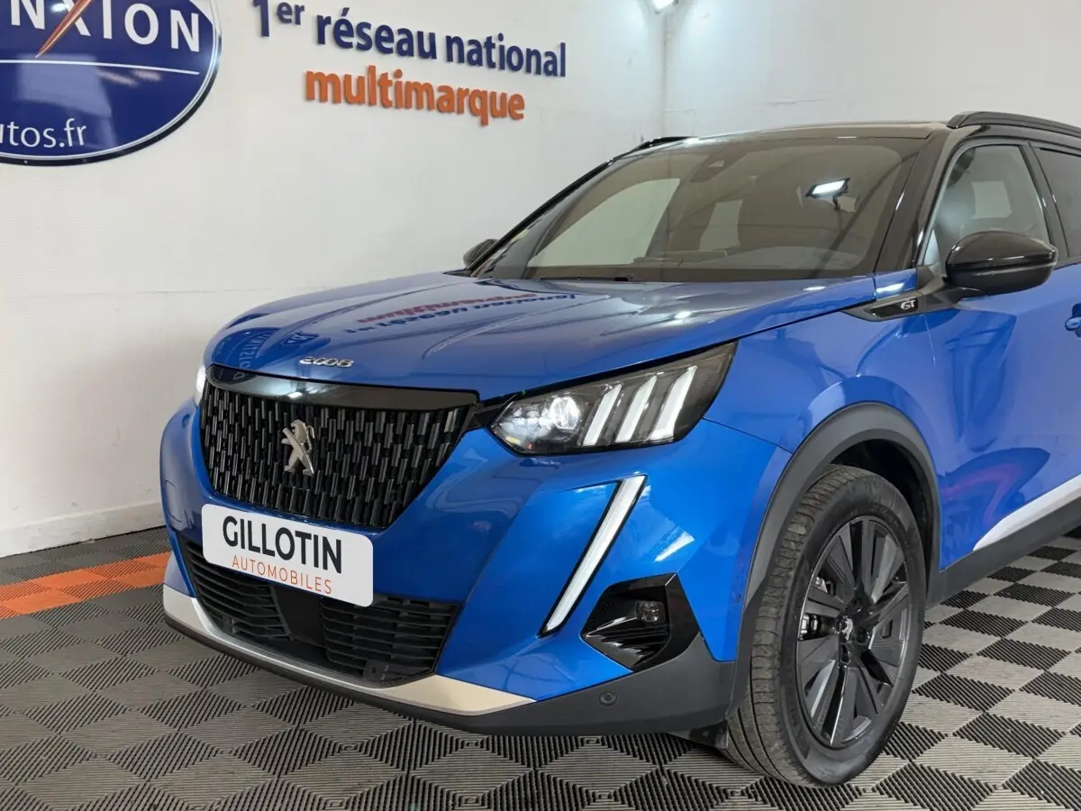 Vue 3/4 avant droit d'un Peugeot 2008 Bleu GT Pack 2021 avec calandre noire et phares LED distinctifs.