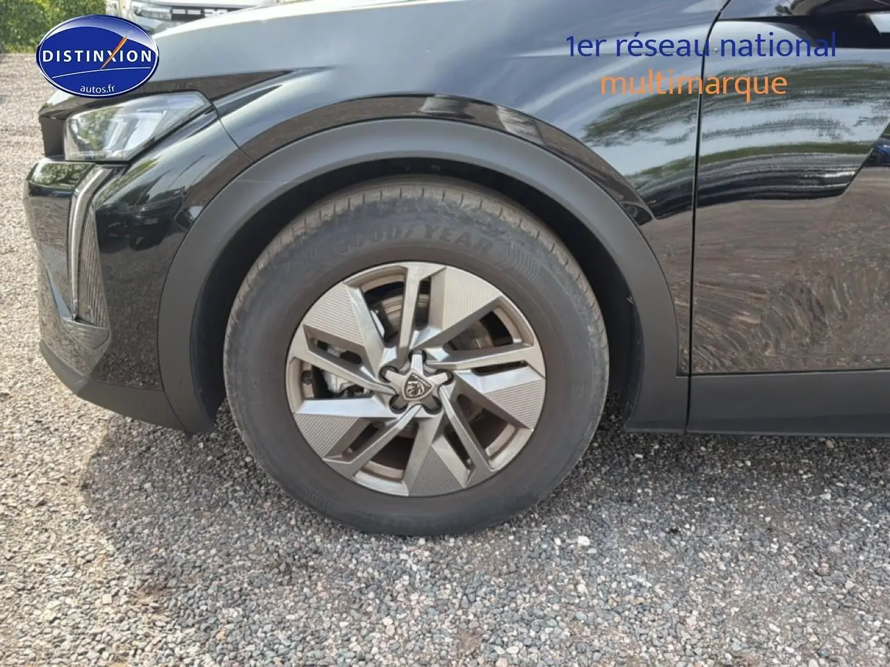 Gros plan sur la roue avant gauche d’une Peugeot 408 bleu foncé avec jante alu au design moderne.