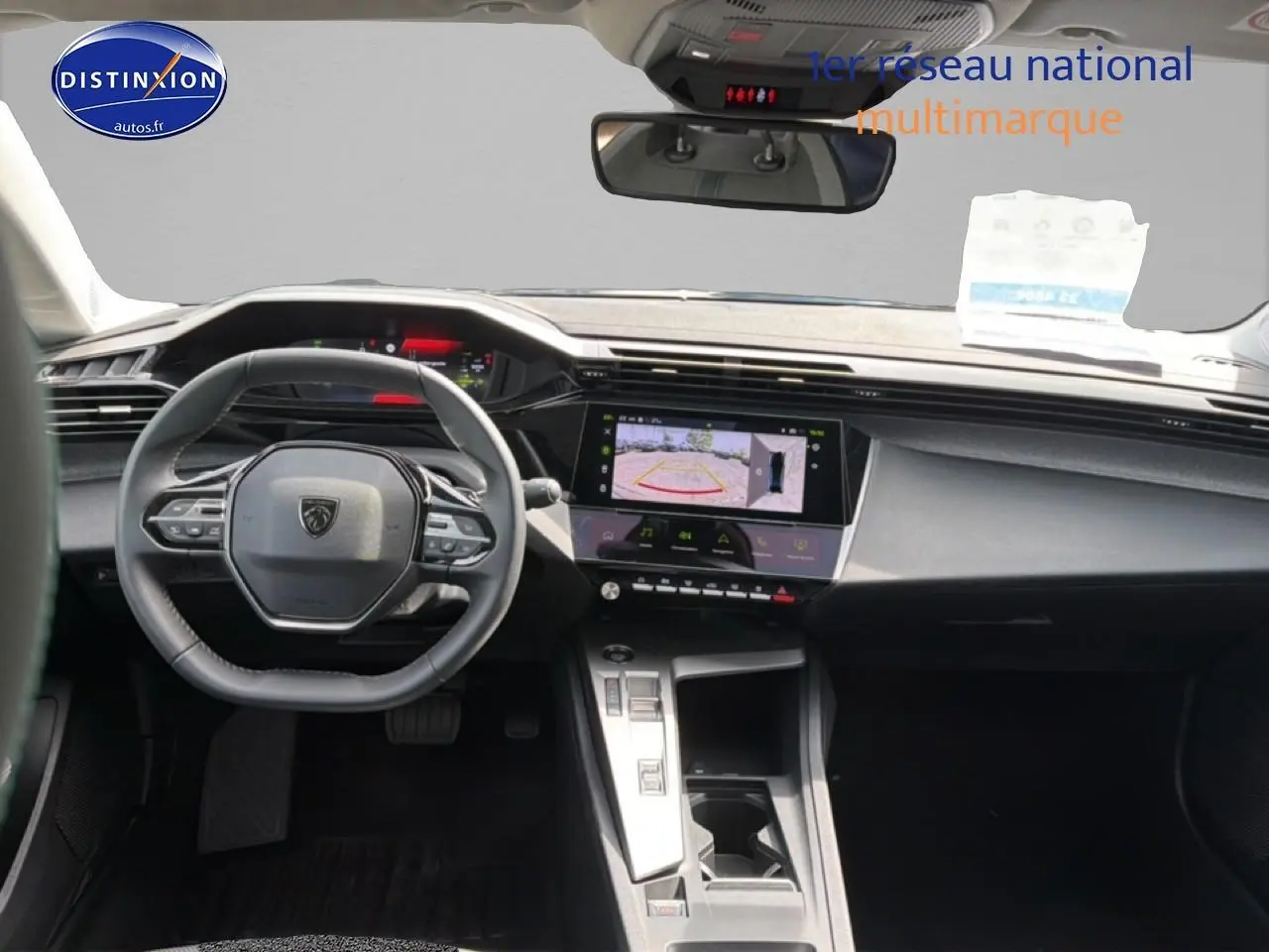 Vue intérieure avant du Peugeot 408 Hybrid 136 allure 2024, volant cuir et écran tactile avec caméra de recul affichée.
