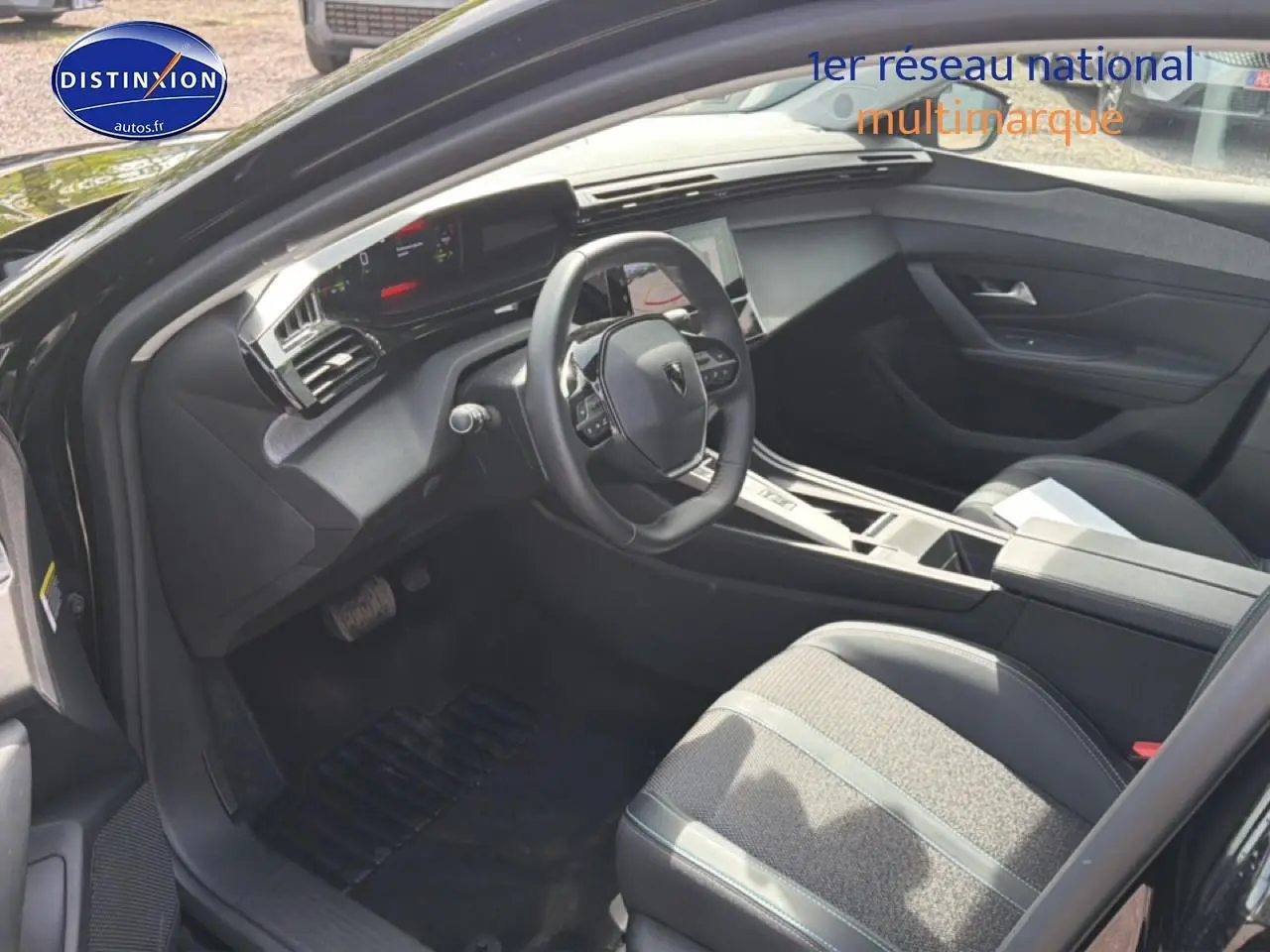 Vue intérieure côté conducteur de la Peugeot 408 Hybrid 136 allure 2024 avec volant cuir et console centrale moderne.