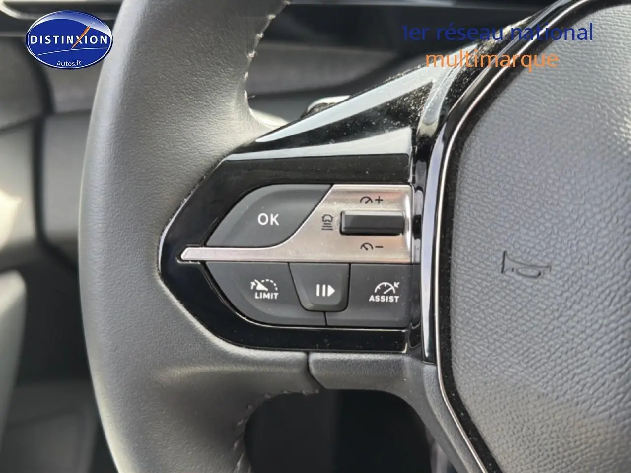 Gros plan sur les commandes du volant cuir noir de la Peugeot 408 Hybrid 136 allure e-dcs6, boutons multifonctions visibles.