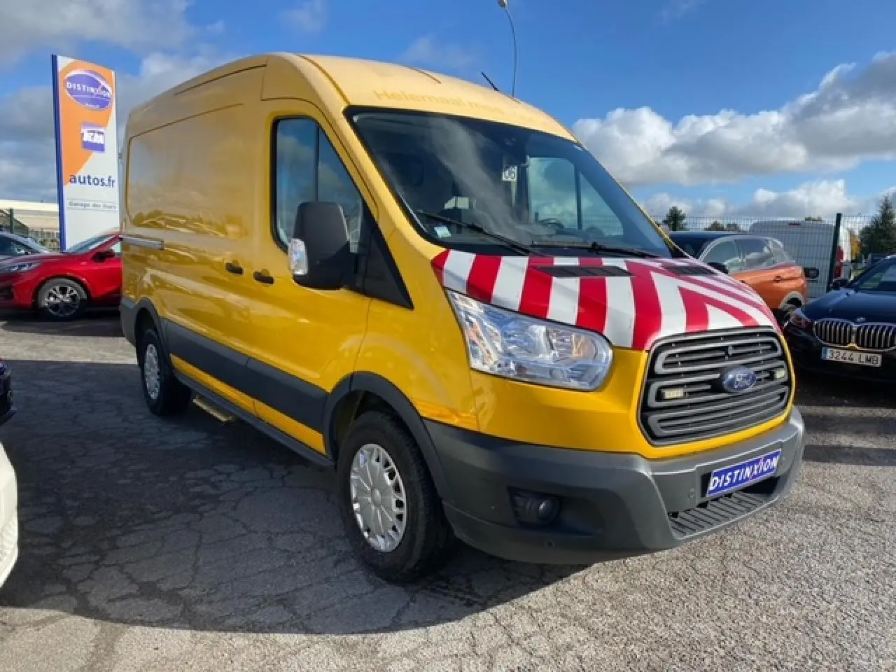 Fourgon Ford Transit orange vu en 3/4 avant droit avec capot rayé rouge et blanc en concession.