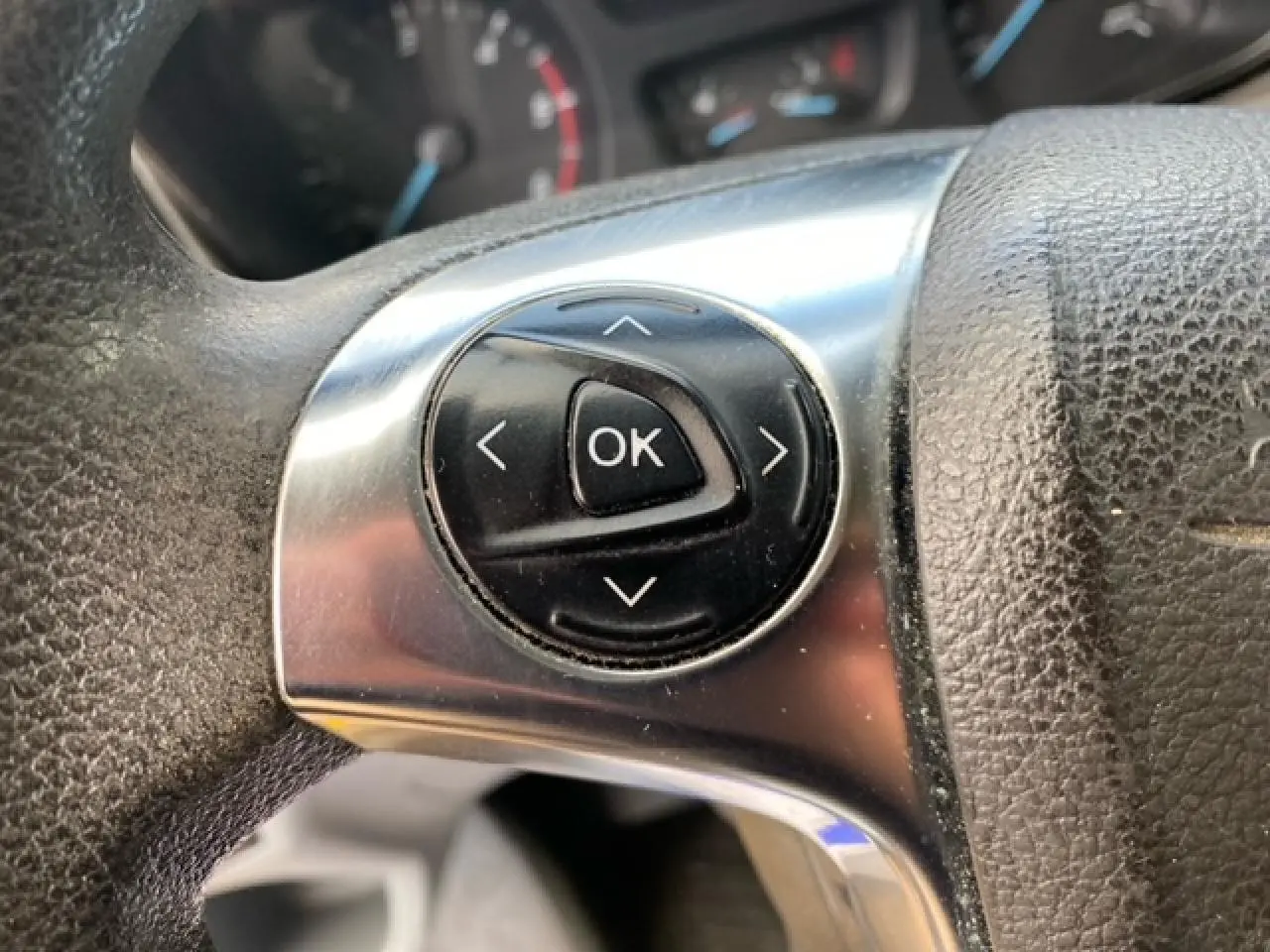 Gros plan sur les commandes noires de validation au centre du volant en cuir noir du Ford Transit Fourgon.