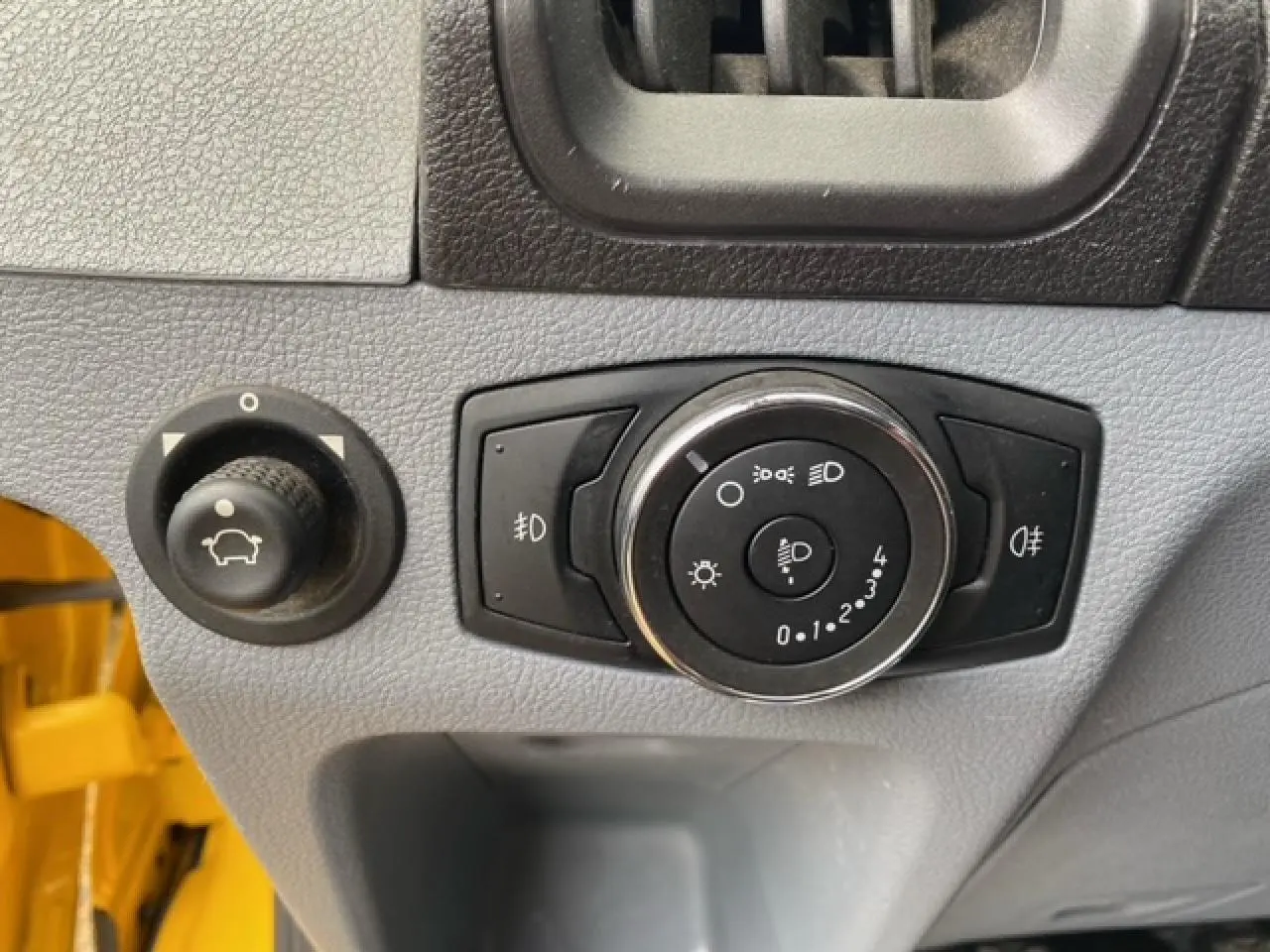 Gros plan sur les commandes d’éclairage et réglage du tableau de bord d’un Ford Transit Fourgon orange 2015.