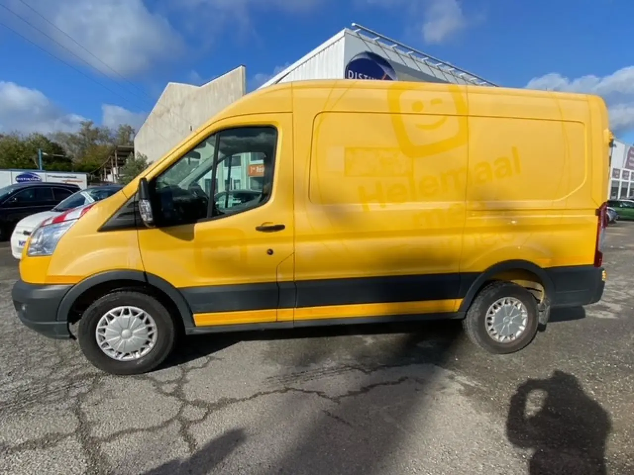 Vue de profil côté gauche d'un Ford Transit Fourgon orange avec porte latérale coulissante et jantes acier.