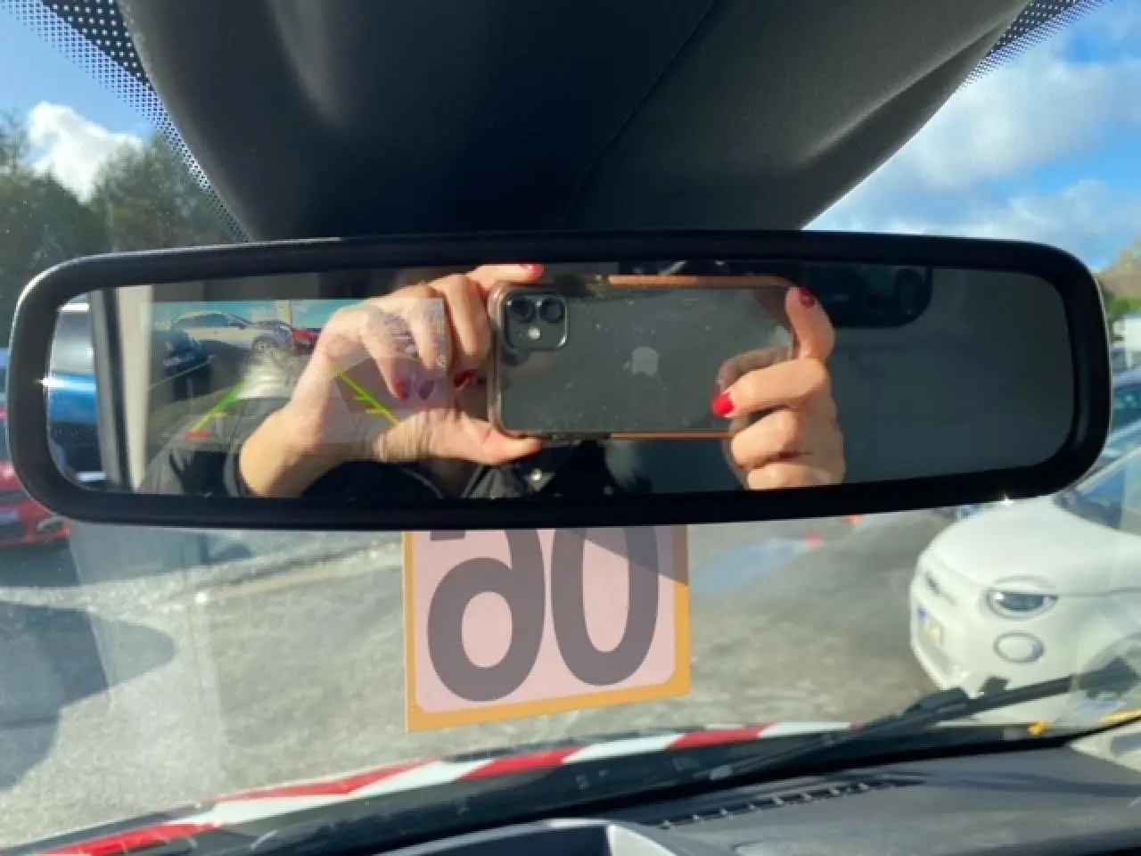 Vue intérieure du rétroviseur central du Ford Transit Fourgon orange, avec reflet du conducteur et caméra de recul visible.