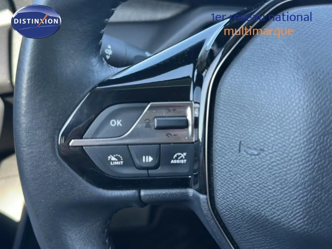 Gros plan sur le volant noir de la Peugeot 308 2021, avec commandes intégrées pour régulateur et limiteur de vitesse.