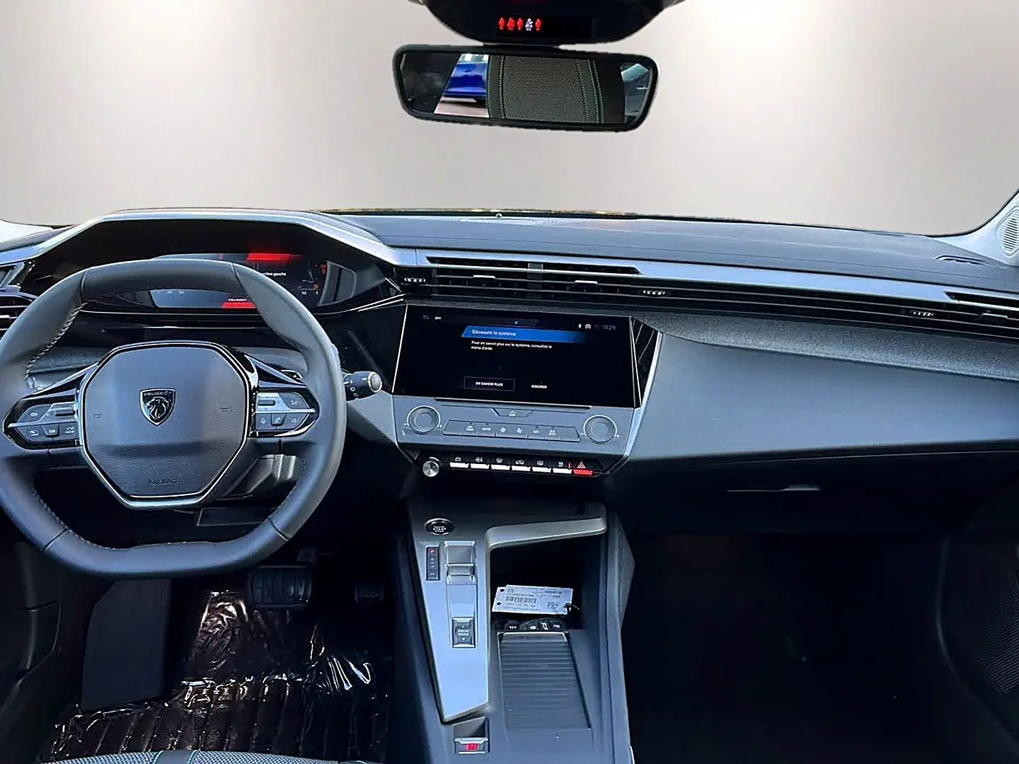 Vue intérieure avant du tableau de bord et volant noir de la Peugeot 308 SW 2025 avec écran tactile central et commandes au volant.