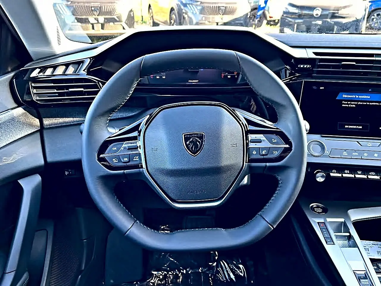 Vue intérieure centrée sur le volant multifonction noir de la Peugeot 308 SW 2025 avec tableau de bord digital et écran tactile.