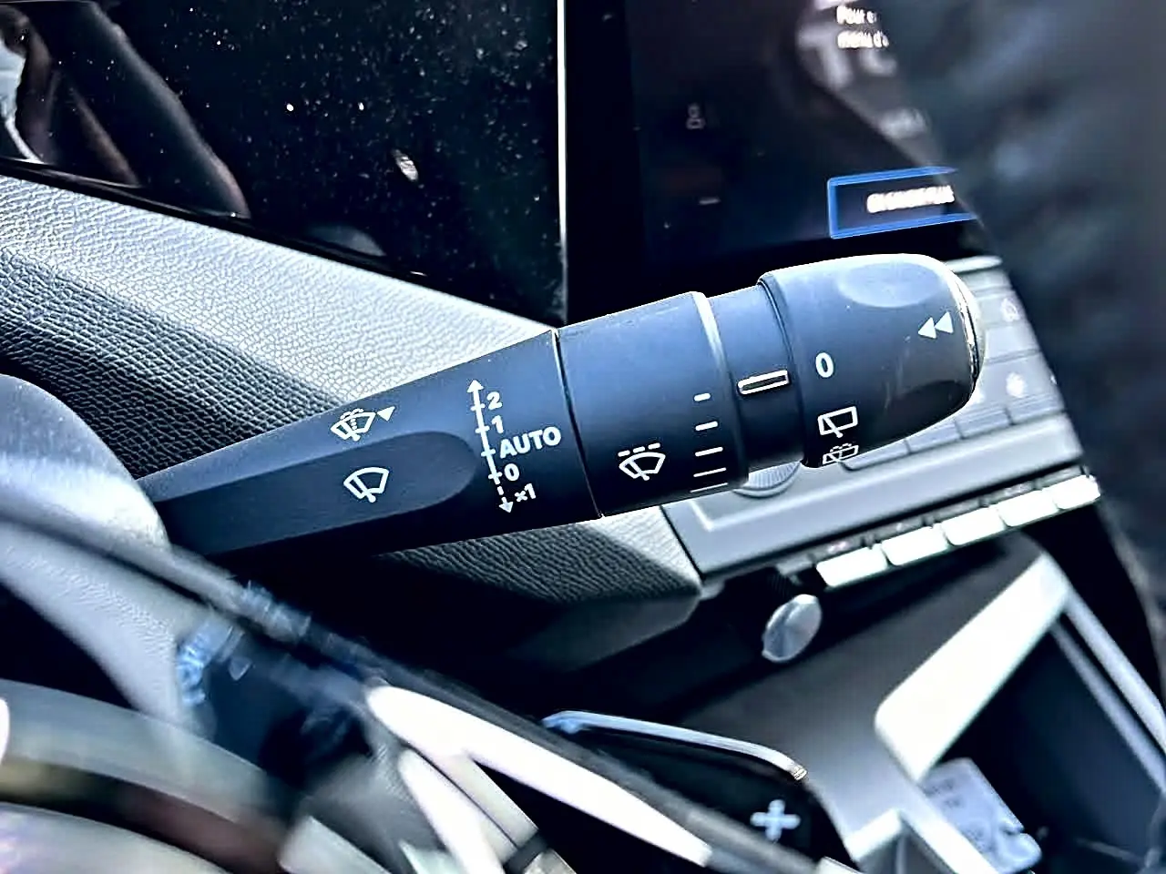 Gros plan sur la commande de l’essuie-glace côté gauche du tableau de bord d’une Peugeot 308 SW noire.