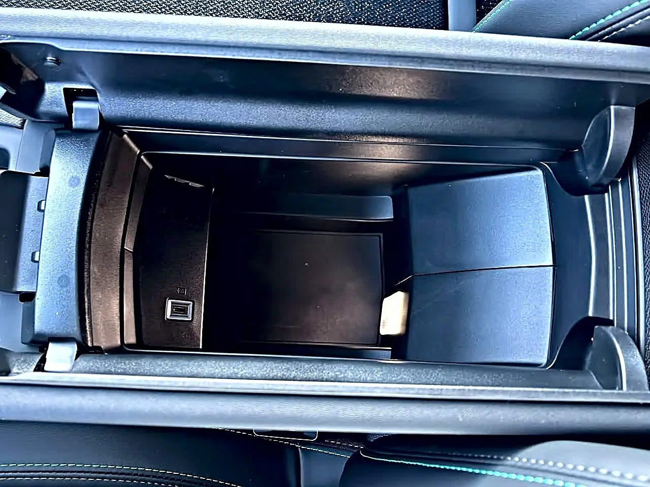 Vue plongeante sur l'accoudoir central avant noir ouvert du Peugeot 308 SW 2025 avec prise USB intégrée.