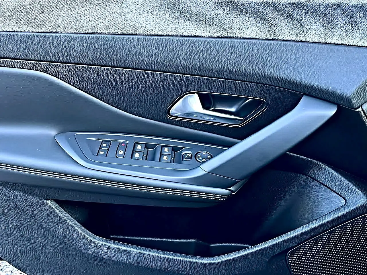 Vue rapprochée de la porte avant gauche noire de la Peugeot 308 SW avec commandes de vitres et rétroviseurs.