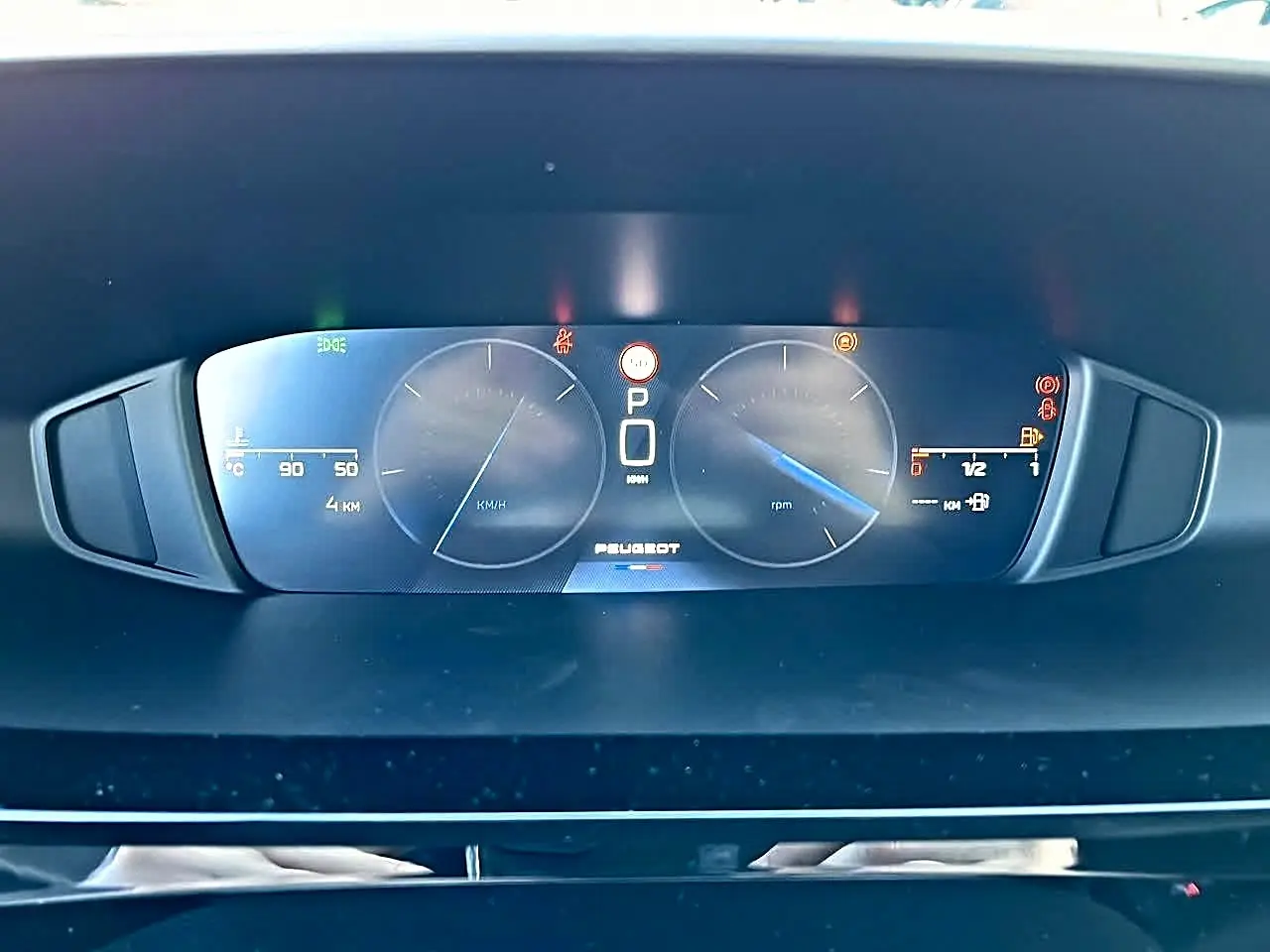 Vue rapprochée du tableau de bord numérique de la Peugeot 308 SW 2025, affichage clair avec logo central et compteurs digitaux.