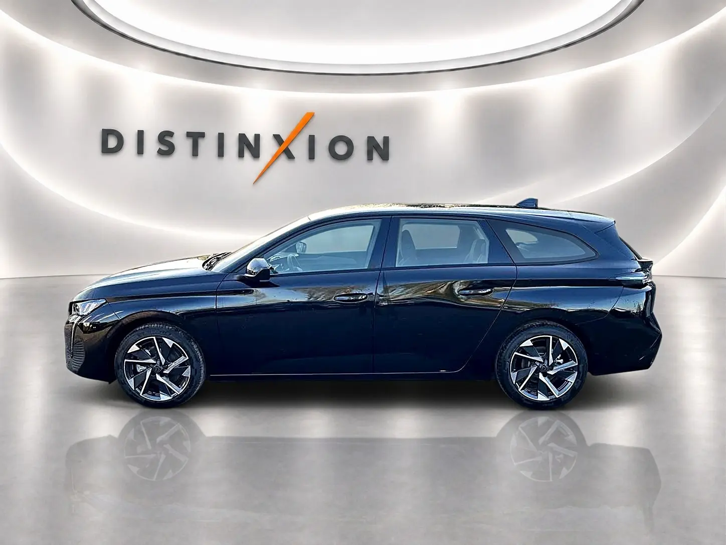 Profil côté gauche d'une Peugeot 308 SW noire 2025 avec jantes alliage et vitres teintées, sur fond lumineux intérieur.
