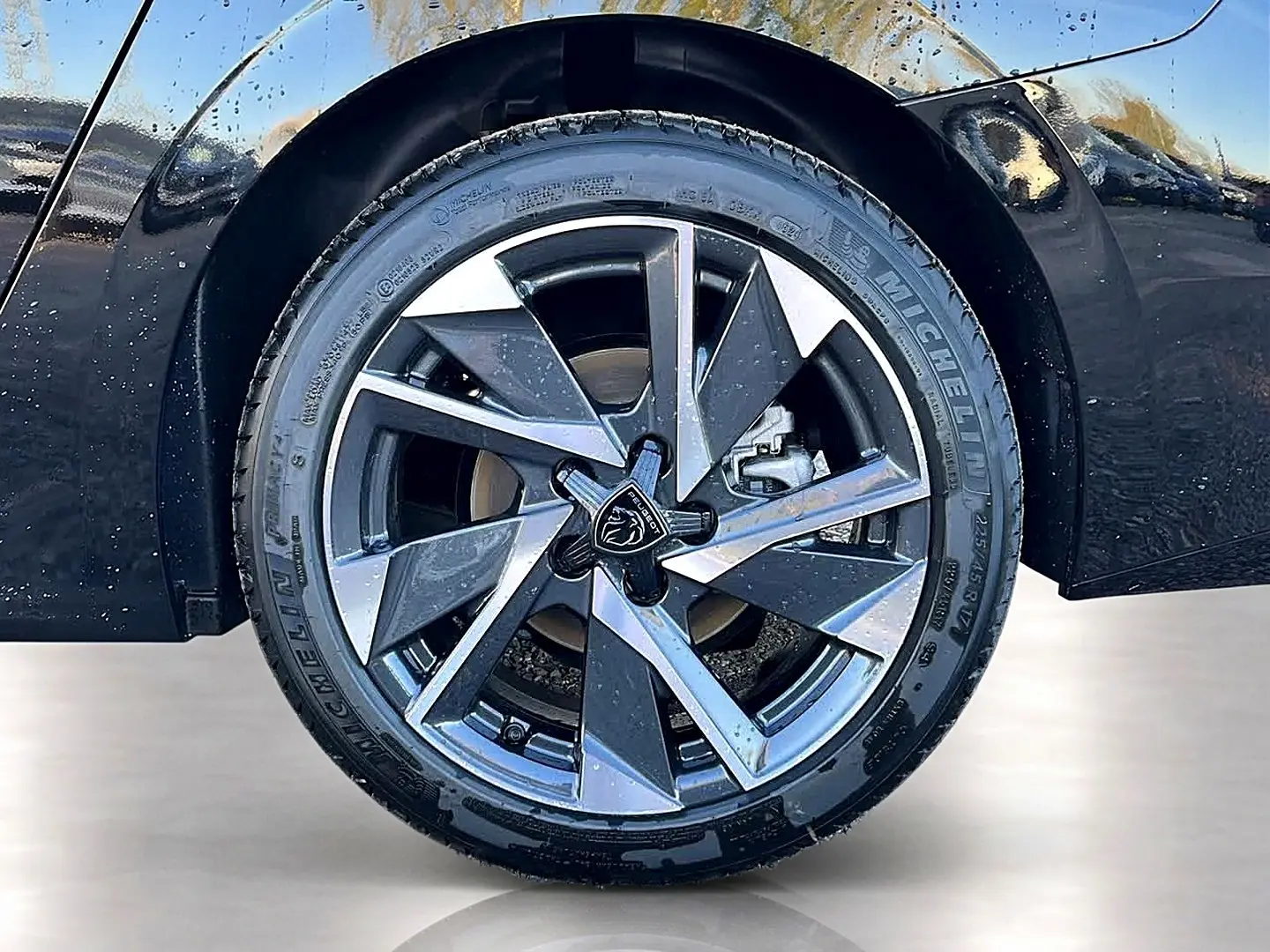 Gros plan sur la jante alu bicolore du côté arrière droit d’une Peugeot 308 SW noire avec pneu Michelin.