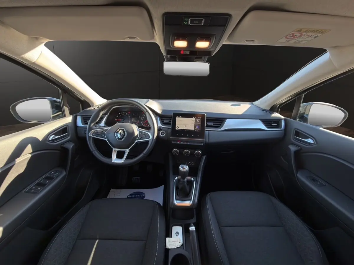Vue intérieure avant du Renault Captur gris foncé 2024, tableau de bord avec écran tactile et volant multifonctions cuir synthétique.