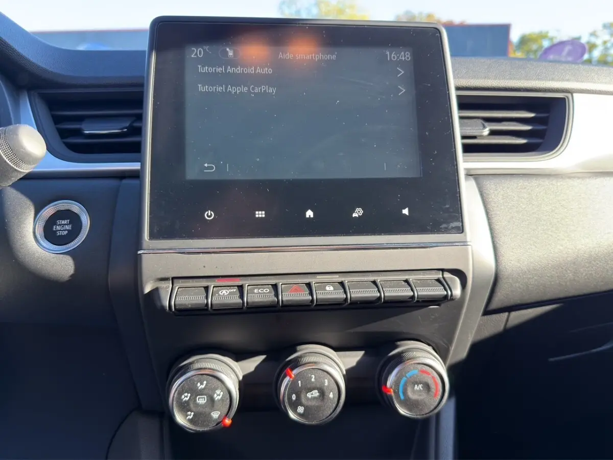 Vue rapprochée de la console centrale du Renault Captur gris foncé 2024, écran tactile et commandes climatisation visibles.
