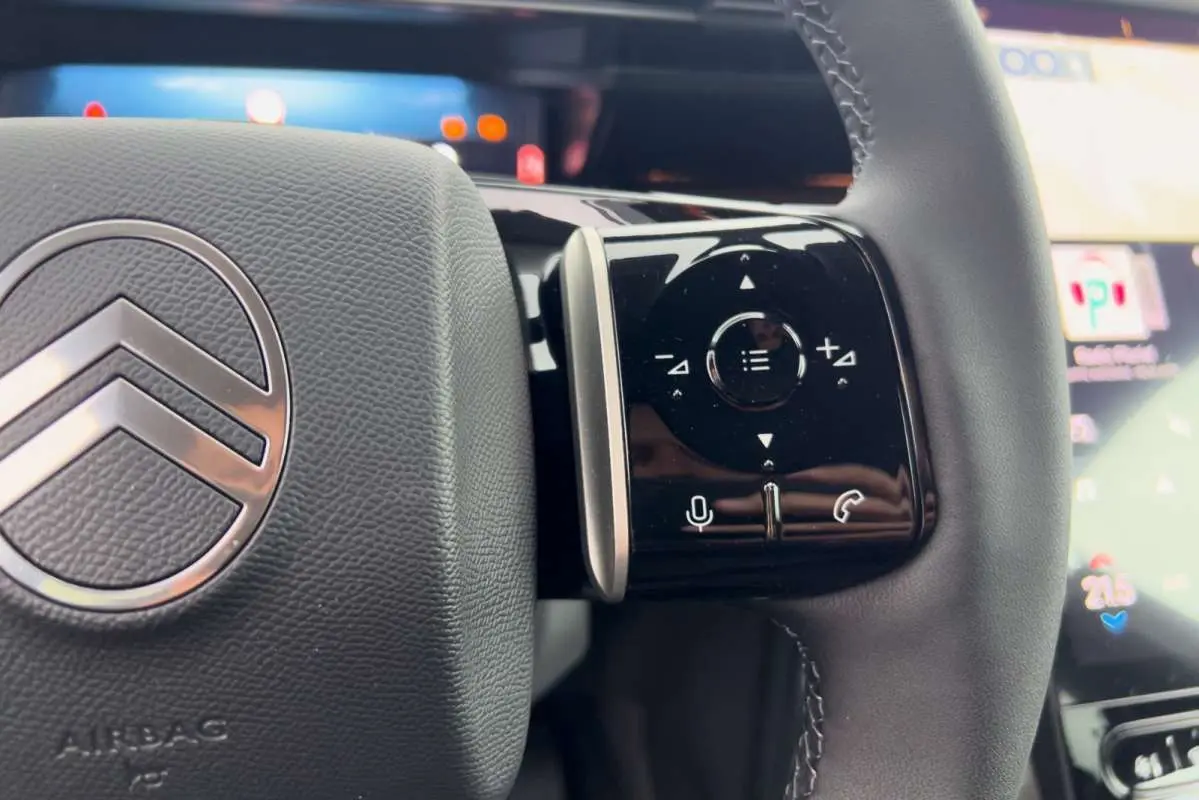 Gros plan sur le volant cuir multifonctions du Citroën C5 Aircross Hybrid 2026 avec commandes tactiles et logo chrome.