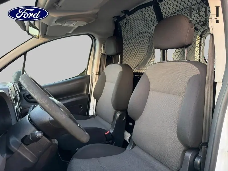 Vue intérieure côté conducteur du Citroën Berlingo blanc 2017, avec sièges gris et cloison tubulaire derrière.