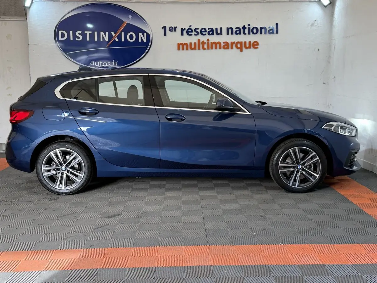 BMW Série 1 116i Business Design bleu vue de profil côté gauche, avec jantes alliage et feux arrière LED.