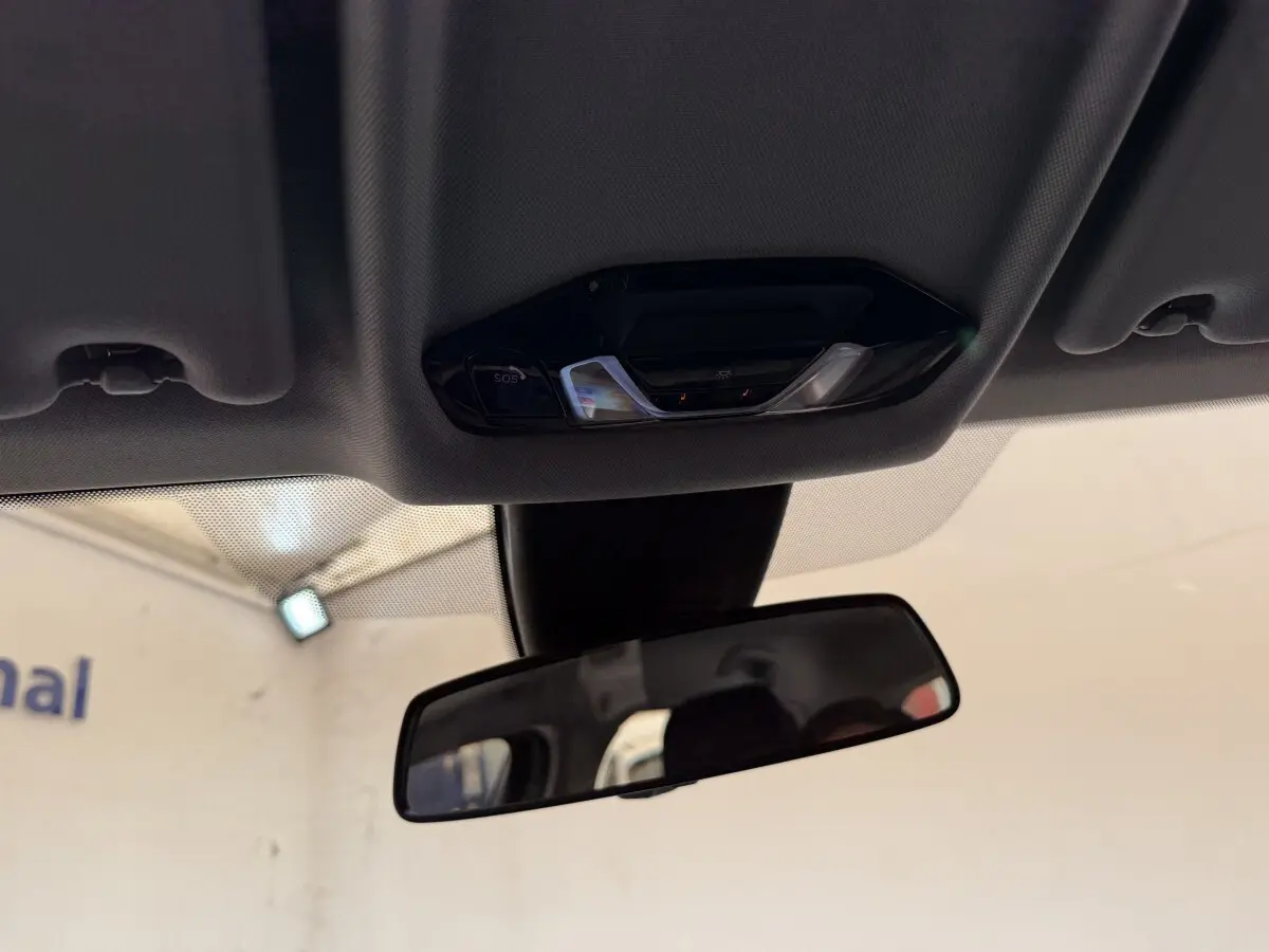 Vue intérieure centrée sur le rétroviseur et la console de plafonnier d’une BMW Série 1 116i 2023.