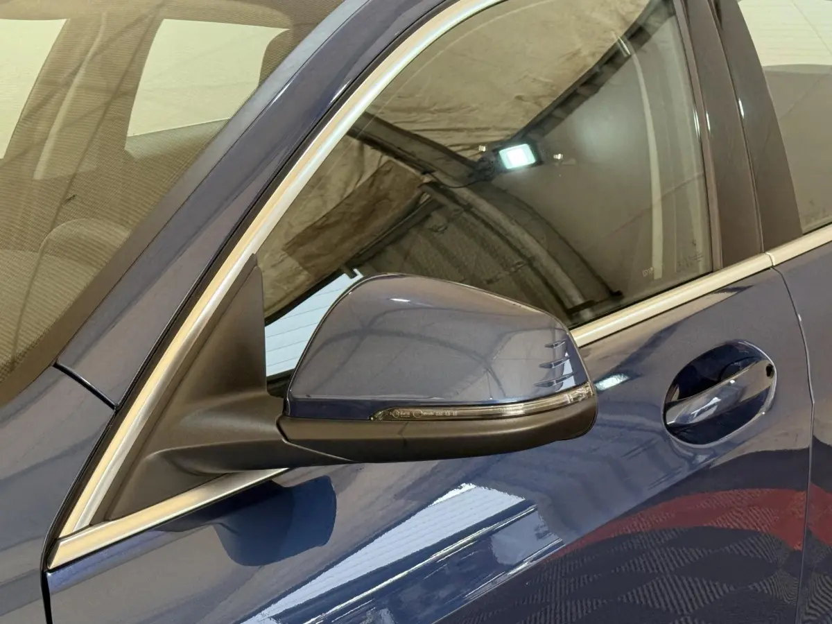 Gros plan sur le rétroviseur côté gauche bleu métallisé de la BMW Série 1 116i Business Design 2023.
