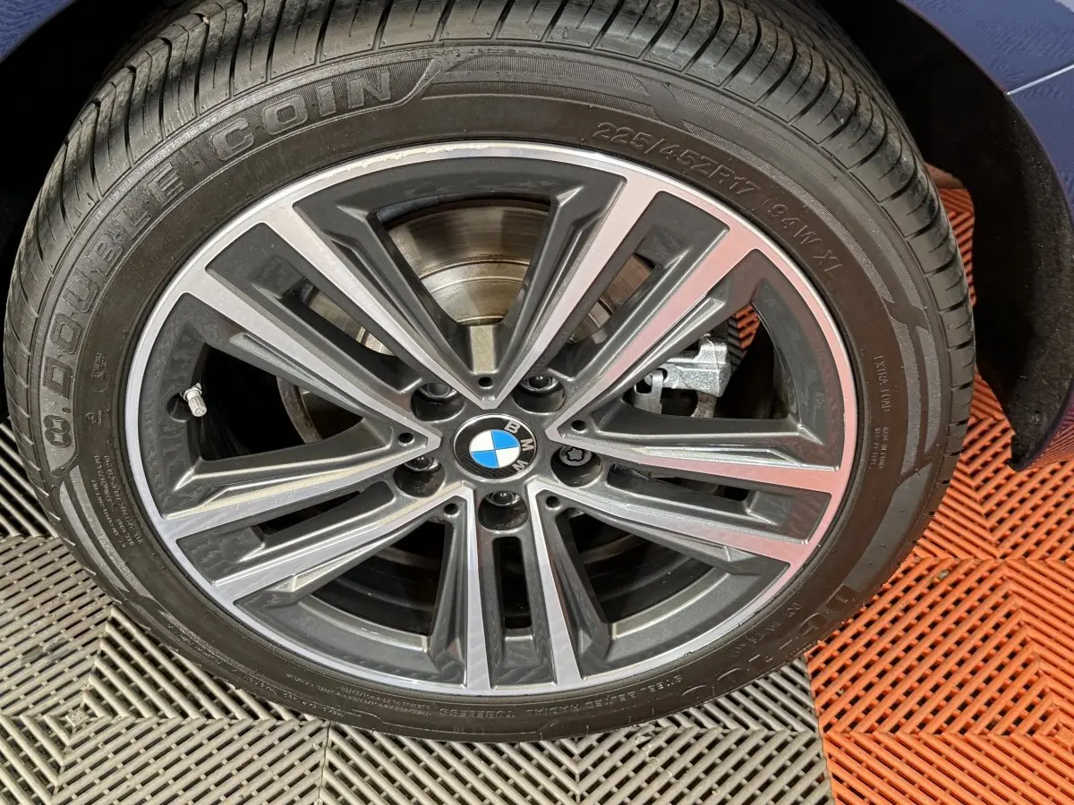 Gros plan sur la roue avant droite de la BMW Série 1 116i Business Design bleu, avec jante alliage à multiples branches.