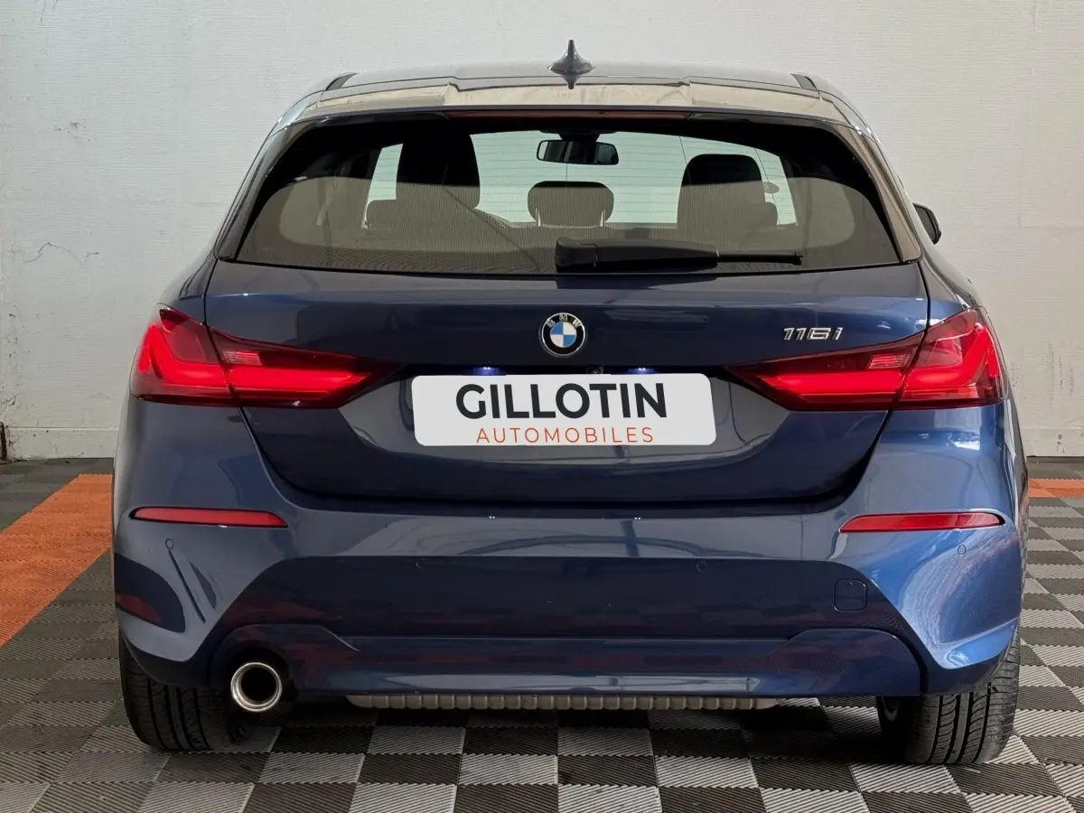 Vue arrière d'une BMW Série 1 116i bleu avec feu LED et sortie d'échappement visible côté gauche.