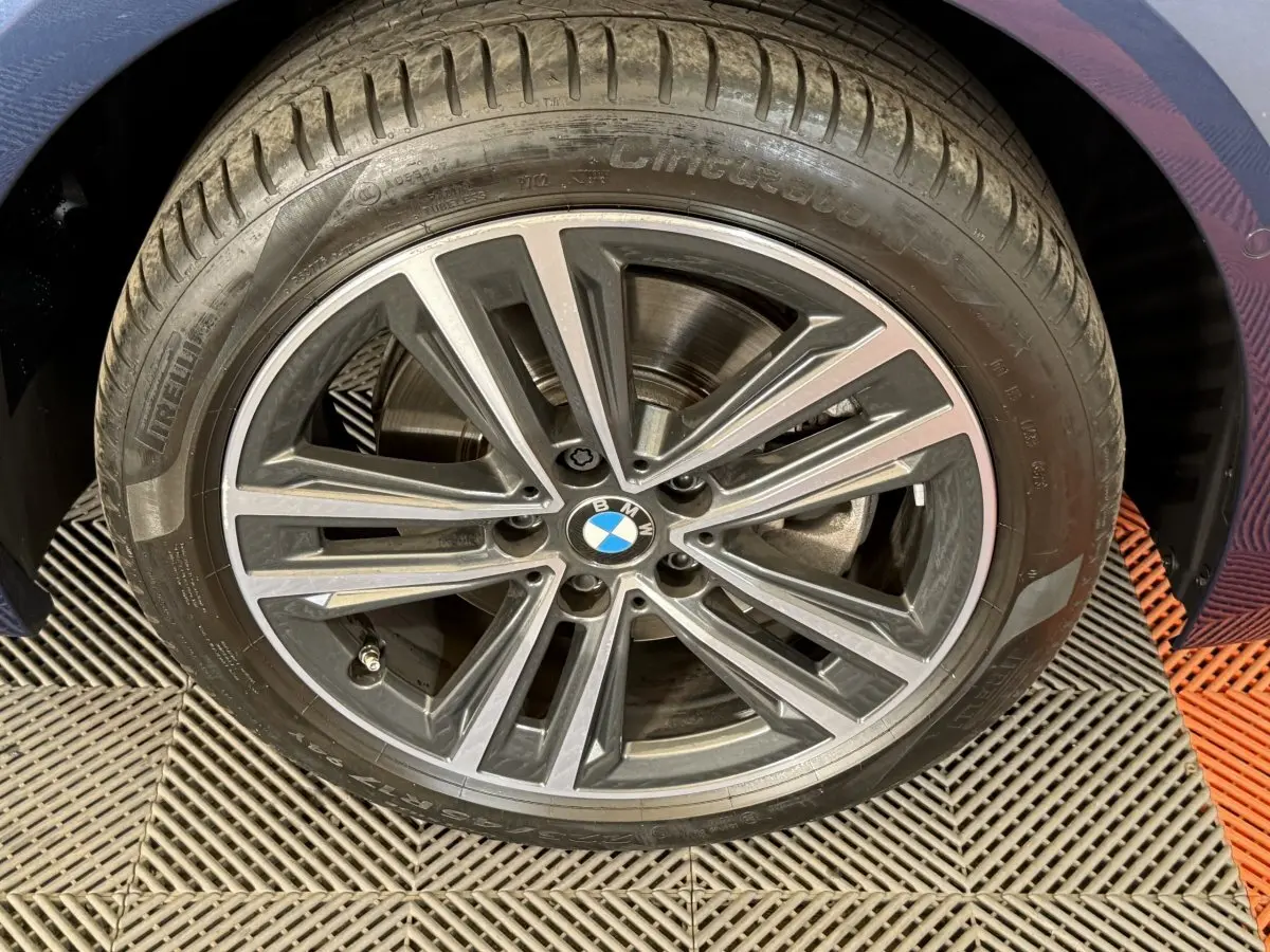 Gros plan sur la jante alliage grise et noire d'une BMW Série 1 116i Business Design bleu, côté droit.