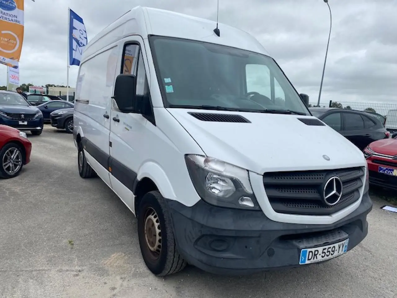 Fourgon Mercedes Sprinter blanc en 3/4 avant droit, avec calandre noire et pare-chocs avant foncé visible.