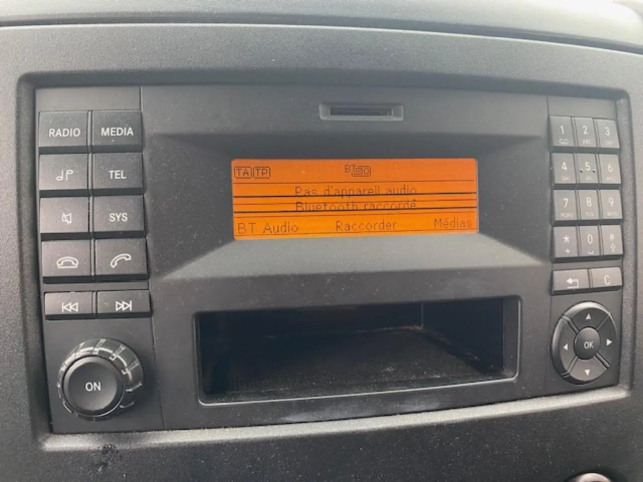 Tableau de bord du Mercedes Sprinter Fourgon 2015 montrant l'autoradio avec écran orange et commandes autour.