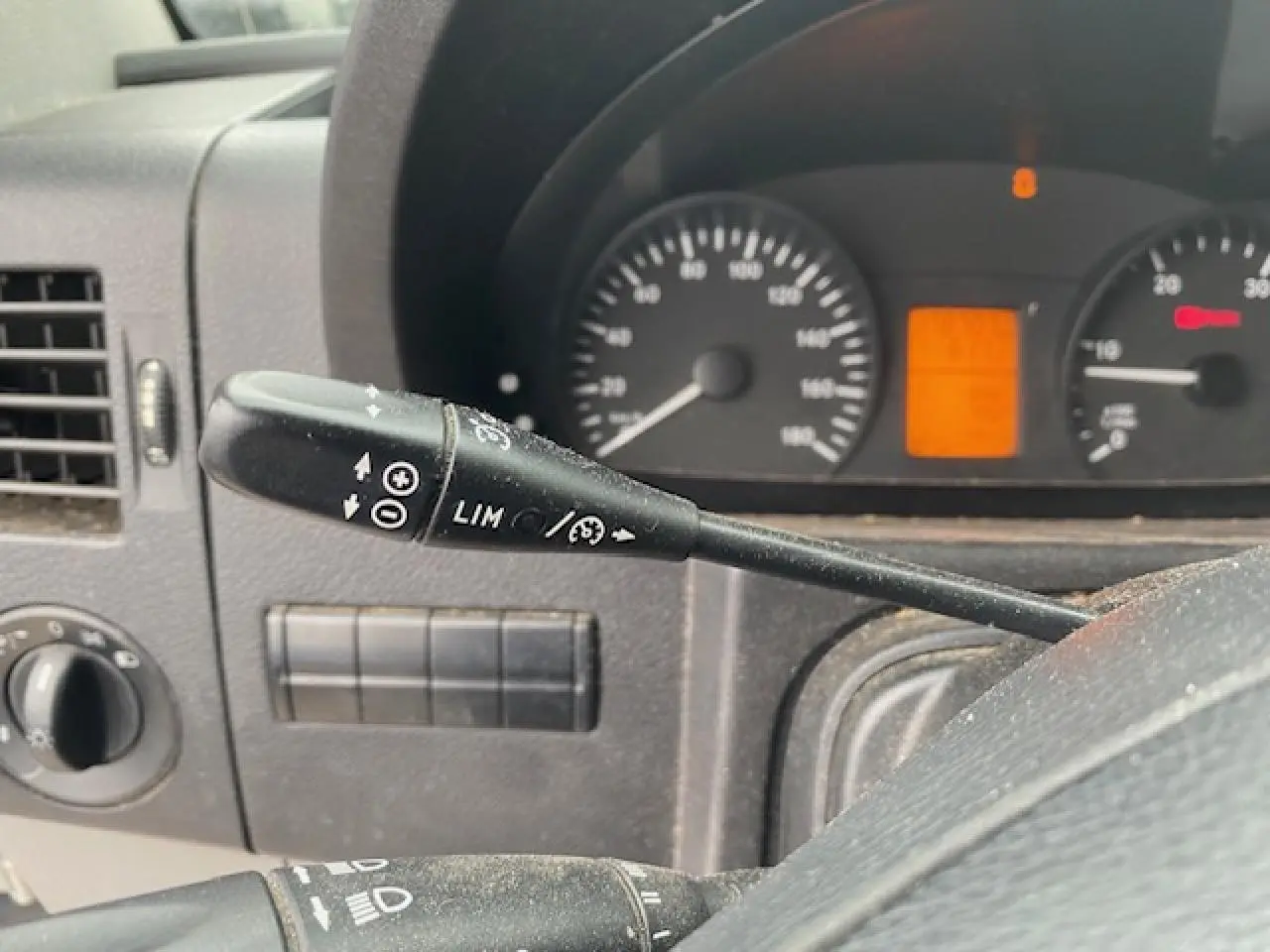 Gros plan sur le commodo de régulateur et limiteur de vitesse du tableau de bord du Mercedes Sprinter blanc de 2015.