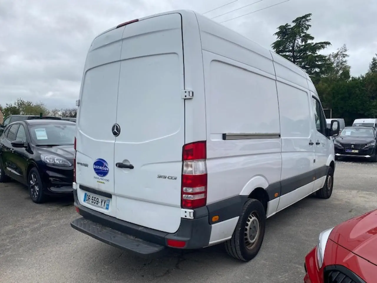 Vue 3/4 arrière droite d’un fourgon Mercedes Sprinter blanc 2015 avec plaques françaises et feux arrière visibles.