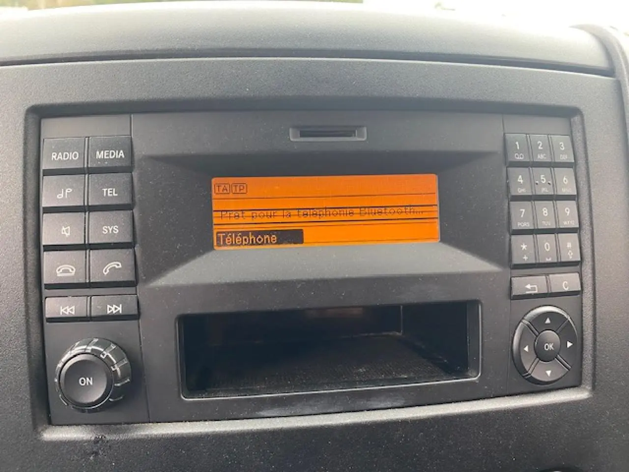 Gros plan sur le tableau de bord du Mercedes Sprinter blanc, affichant l’écran radio avec menu téléphone Bluetooth.