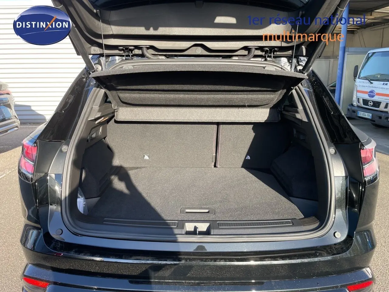 Coffre ouvert en vue arrière d’un Renault Austral noir étoile métal, montrant l’espace de chargement vide et la plage arrière relevée.