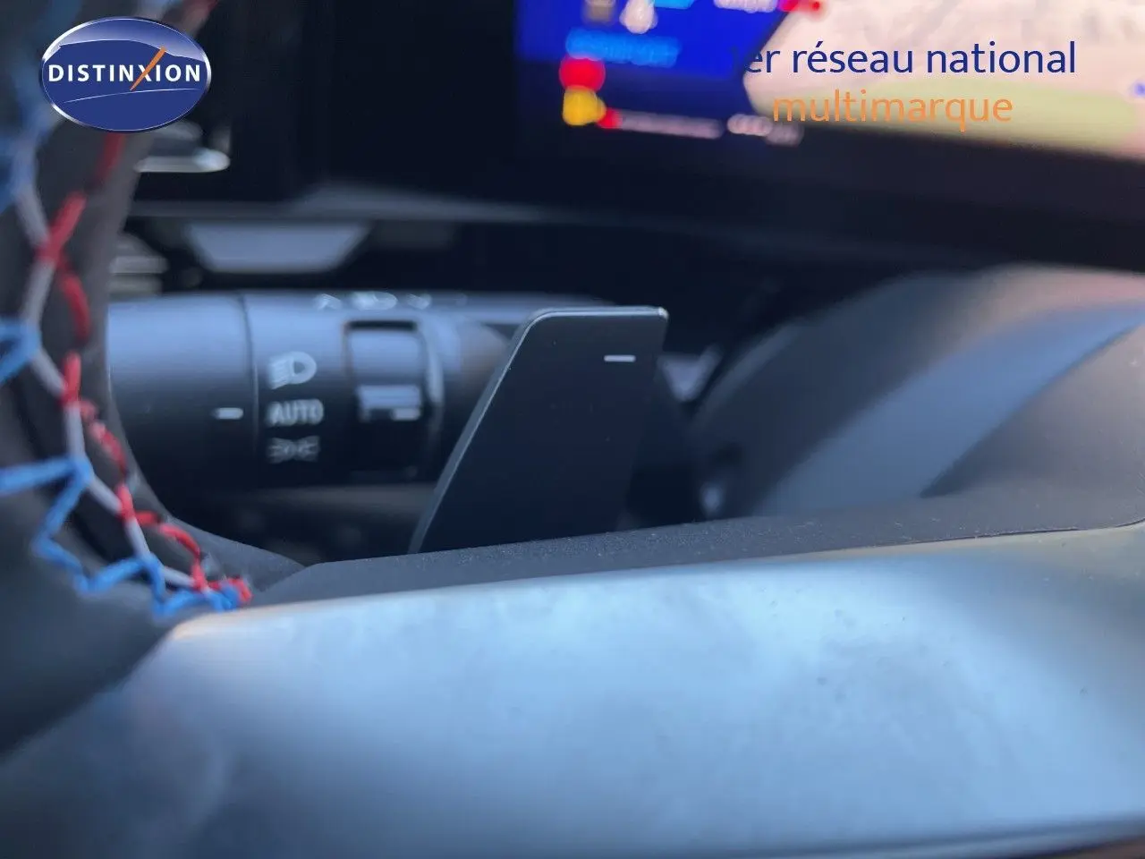 Gros plan sur la palette de changement de vitesse noire du volant cuir tricolore rouge, bleu et noir du Renault Austral 2026.