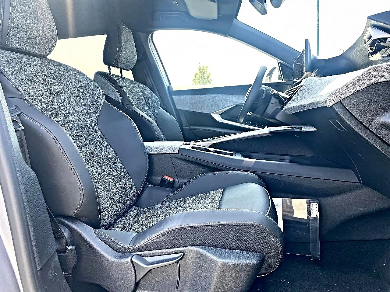 Vue intérieure côté conducteur du Peugeot 5008 Hybrid 145 allure e-dcs6, sièges tissu gris et cuir noir, tableau de bord moderne.