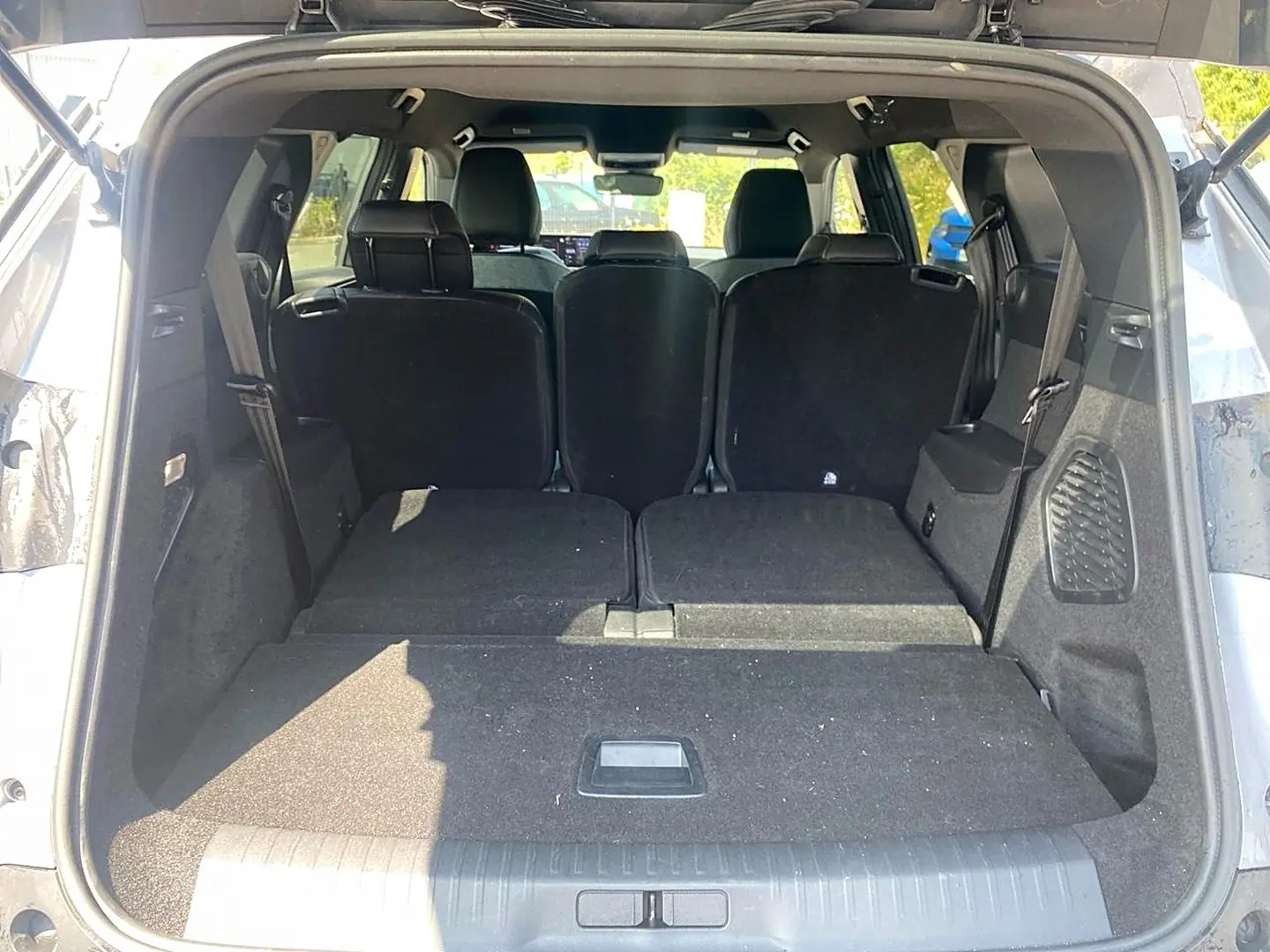 Coffre ouvert d’un Peugeot 5008 gris Artense, vue arrière montrant les sièges rabattus et l’espace de chargement plat.