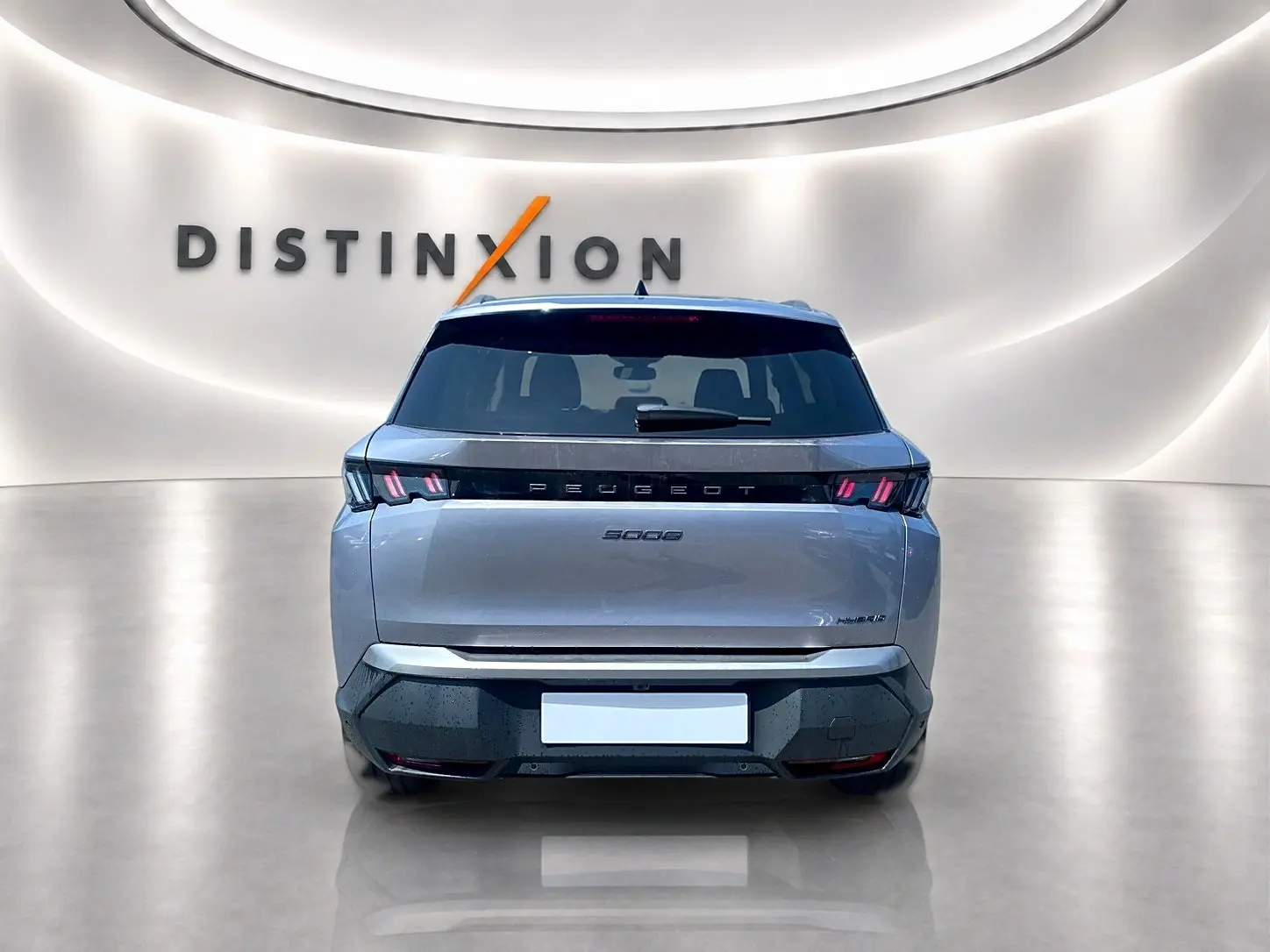 Vue arrière d’un Peugeot 5008 Hybrid 145 allure e-dcs6 gris artense avec feux LED et logo distinctif sur fond lumineux.