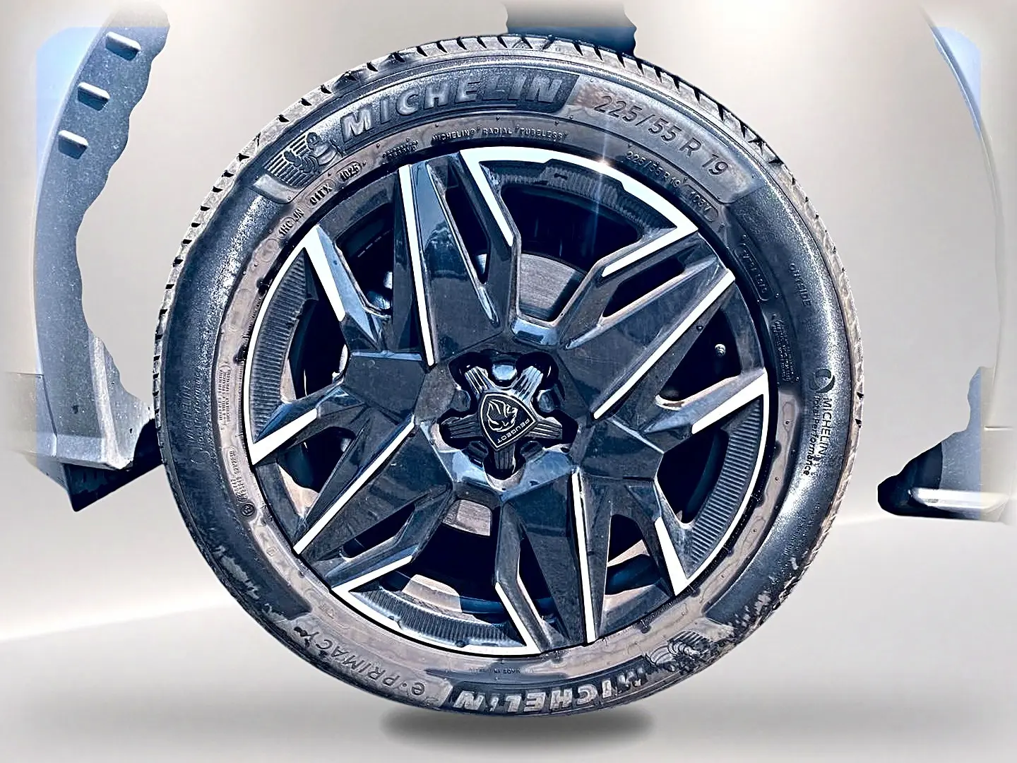 Gros plan sur la jante alu noire et argentée d’un Peugeot 5008 gris Artense, mettant en valeur le logo central Peugeot.