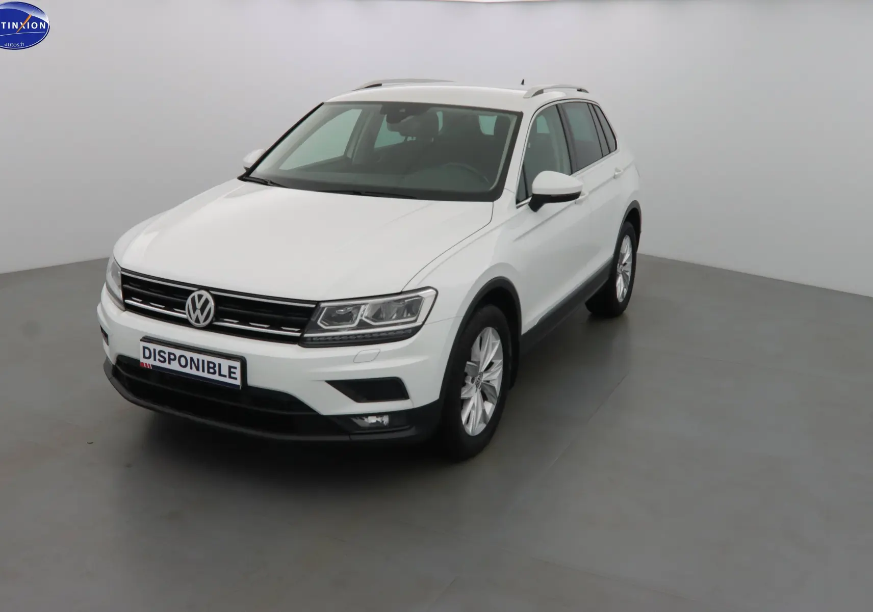 Volkswagen Tiguan blanc en 3/4 avant droit, avec calandre noire et jantes alliage visibles.