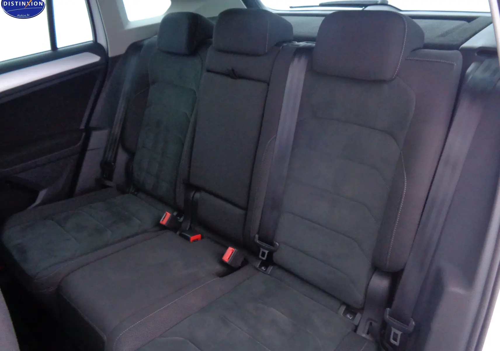 Vue intérieure montrant les sièges arrière en tissu gris foncé du Volkswagen Tiguan blanc 2019, avec ceintures de sécurité visibles.