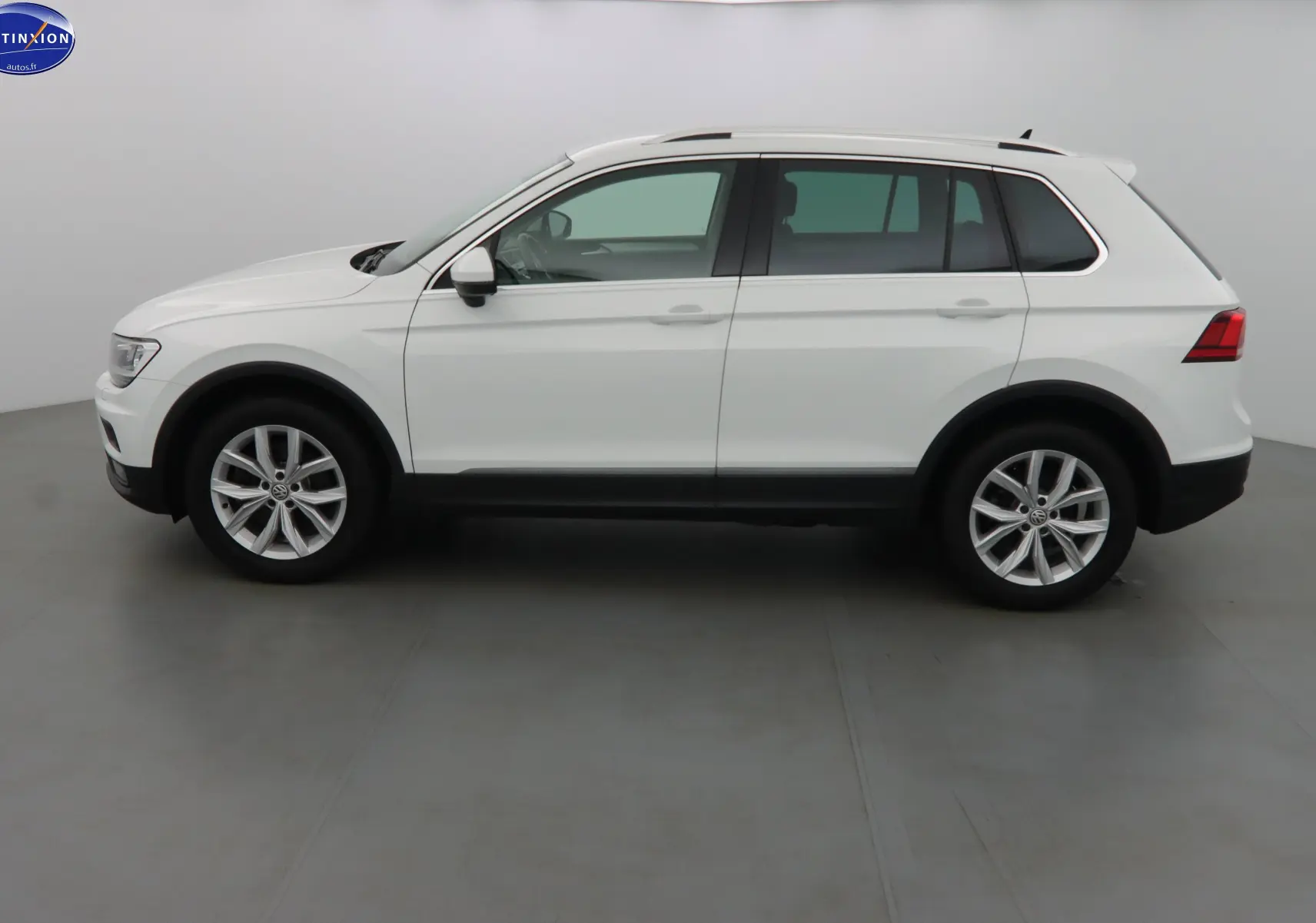 Vue de profil côté gauche d'un Volkswagen Tiguan blanc 2019 avec jantes alliage et protections noires sur les bas de caisse.