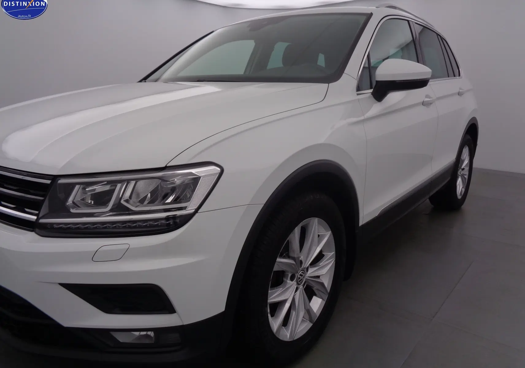 Volkswagen Tiguan blanc vu en 3/4 avant droit, mettant en valeur ses phares LED et jantes alliage.