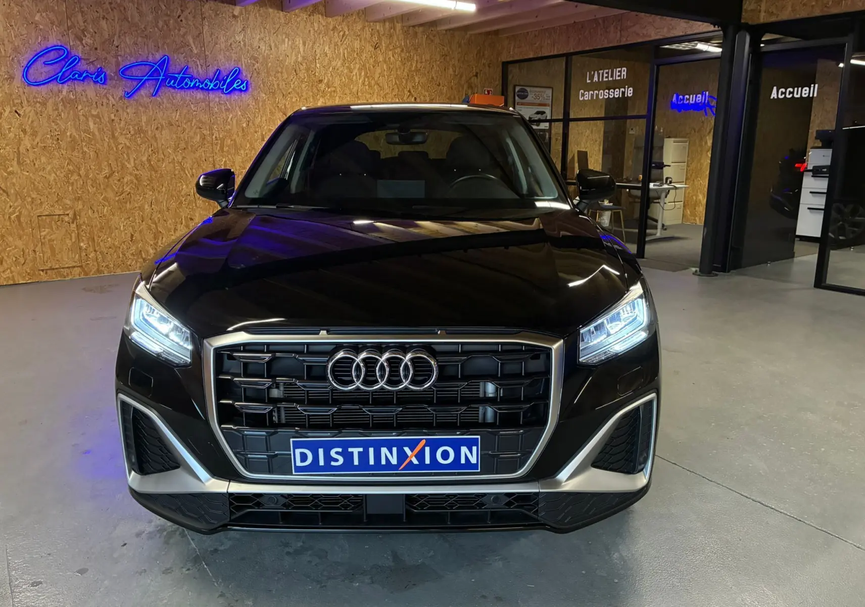Audi Q2 noir vue de face en intérieur, avec calandre S-Line et phares LED allumés.