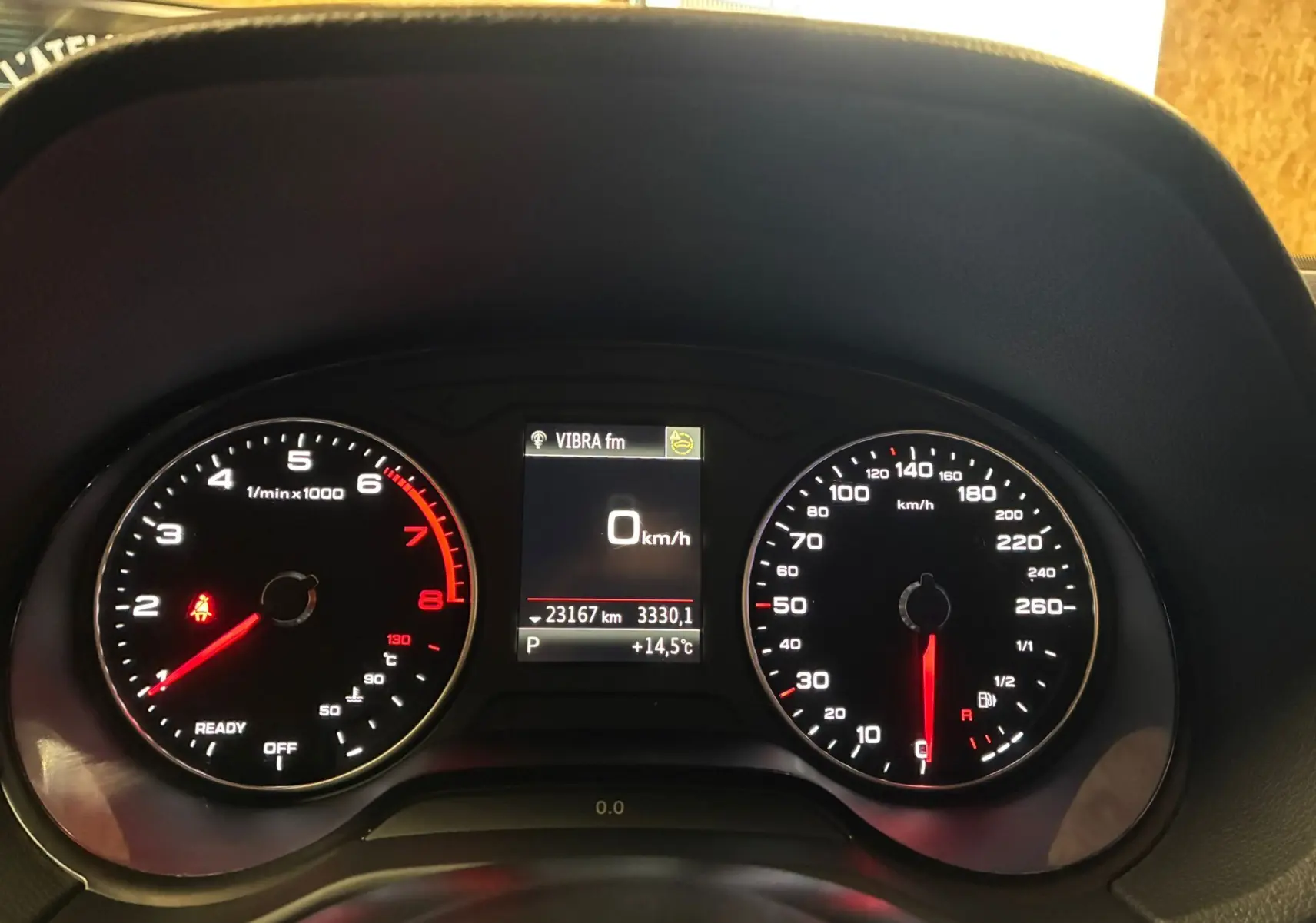 Tableau de bord de l'Audi Q2 noir, affichant compte-tours, vitesse à 0 km/h et écran central avec température et kilométrage.