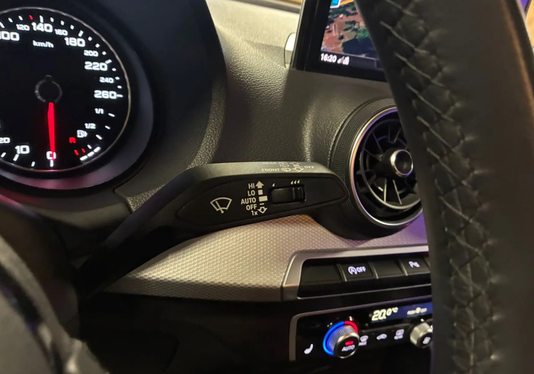 Vue rapprochée du tableau de bord noir de l'Audi Q2 2023, avec commandes d'essuie-glace et ventilation circulaire.