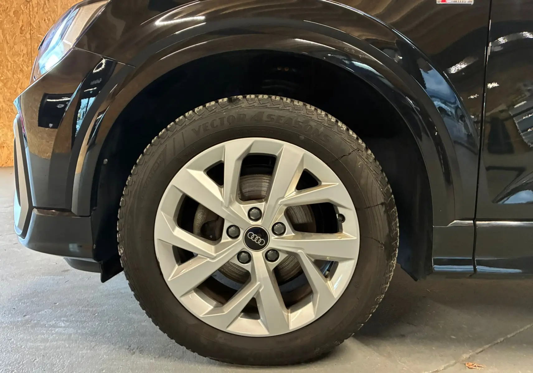 Gros plan sur la roue avant gauche d'un Audi Q2 noir 35 TFSI S-Line avec jante argentée et logo Audi central.