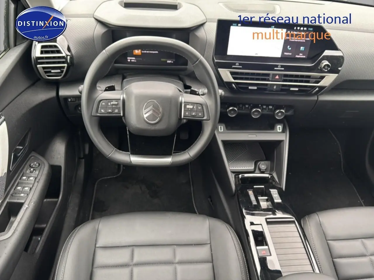 Vue intérieure avant centrée sur le volant cuir noir et la console centrale brillante de la Citroën C4 hybride 2025.