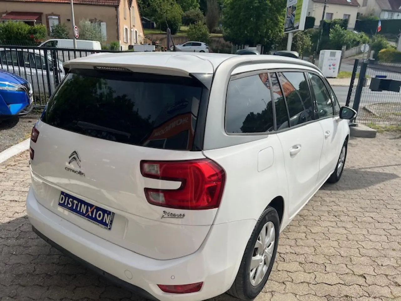 Vue 3/4 arrière droite d’un Citroën Grand C4 Picasso blanc avec vitres surteintées et jantes alliage 16 pouces.